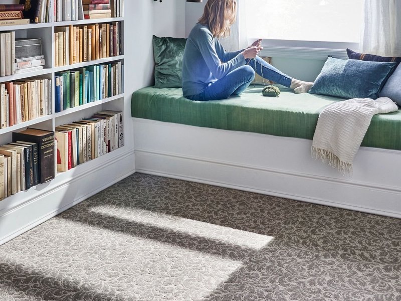Person reading in window in bedroom with brown patterned carpet from Carpet City & Flooring Center in the Fairfield, CT area